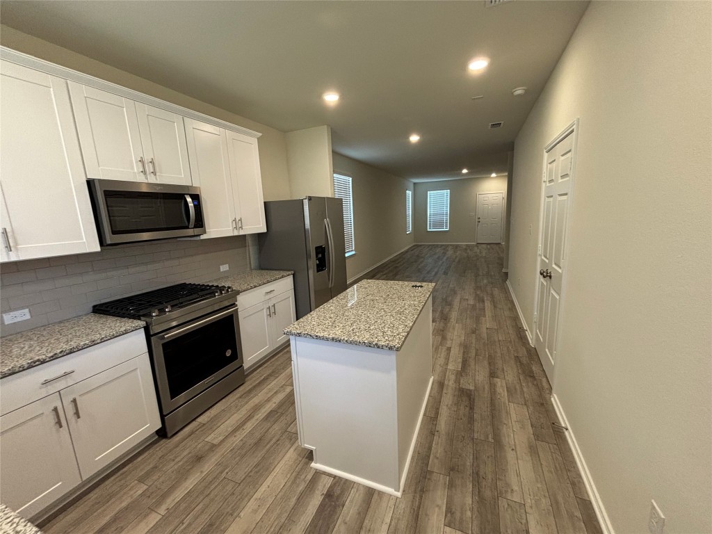 344 Tree Nut Loop Buda, TX 78610 - Photo 5 of 22 a kitchen with granite countertop a stove top oven a sink dishwasher and a refrigerator with wooden floor