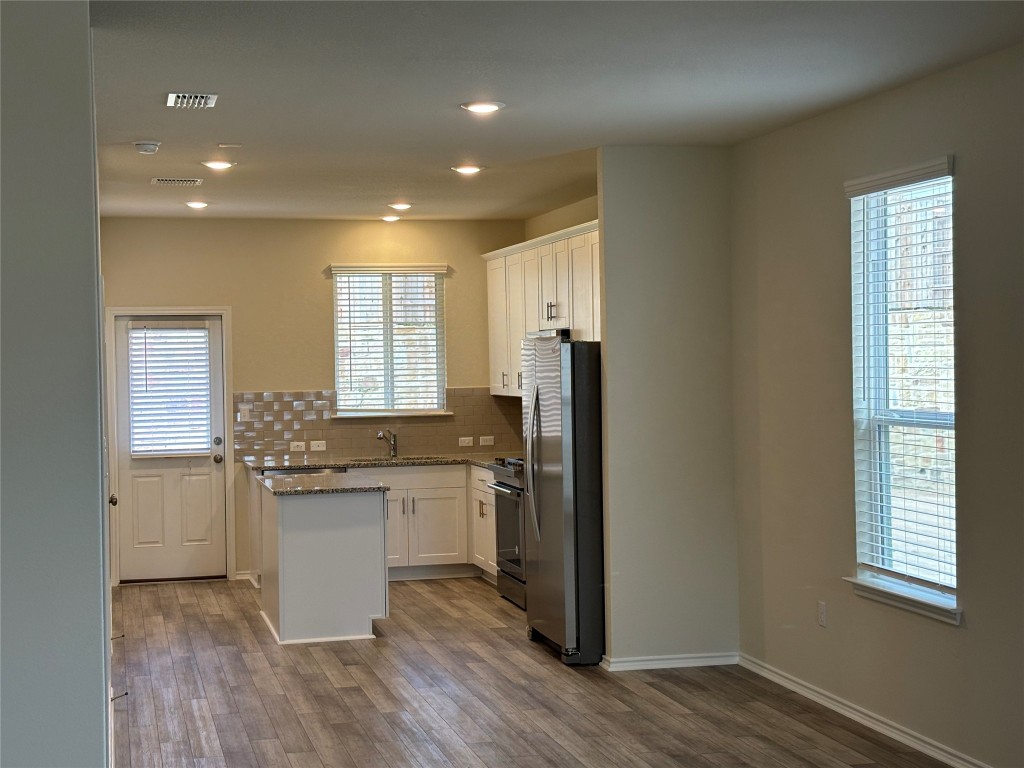 344 Tree Nut Loop Buda, TX 78610 - Photo 9 of 22 a kitchen with stainless steel appliances granite countertop a refrigerator a sink dishwasher a stove and white countertops with wooden floor