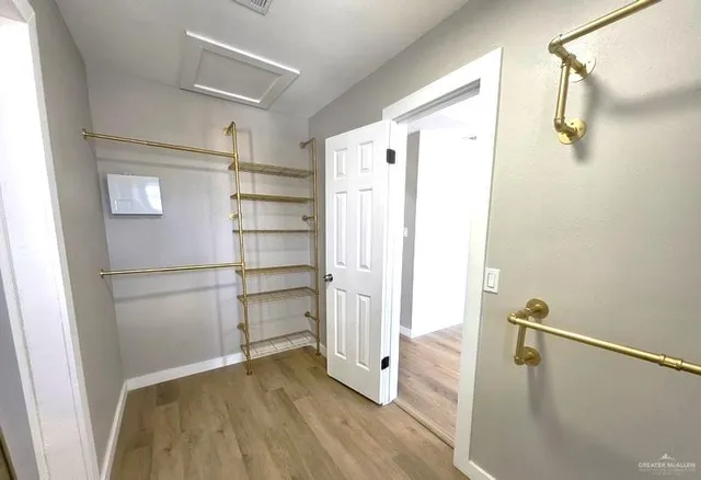 an empty room with a chandelier fan and wooden floor