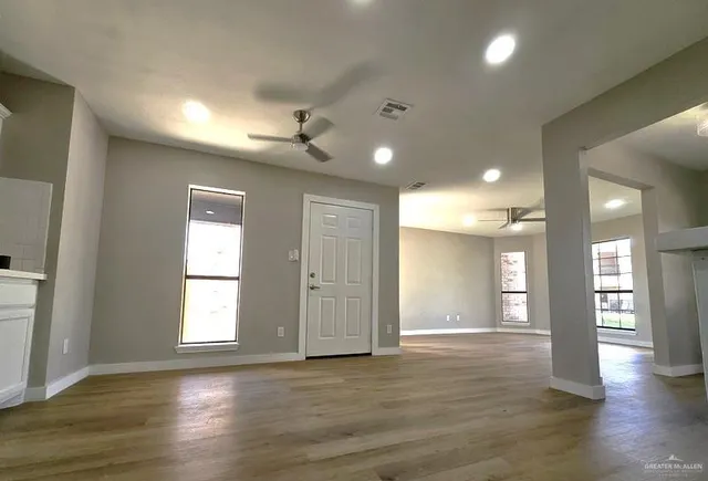 an empty room with wooden floor and windows