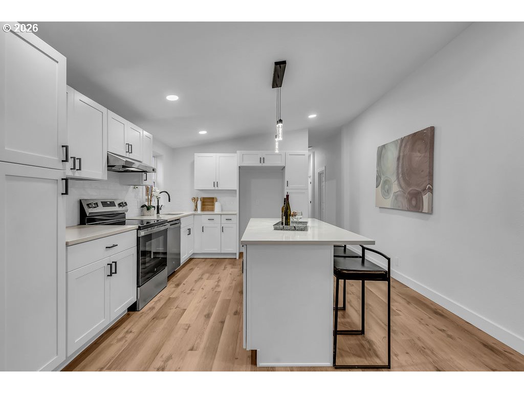 241 Northwest Wade Street Estacada, OR 97023 - Photo 18 of 45 a kitchen with kitchen island a sink stove and white cabinets