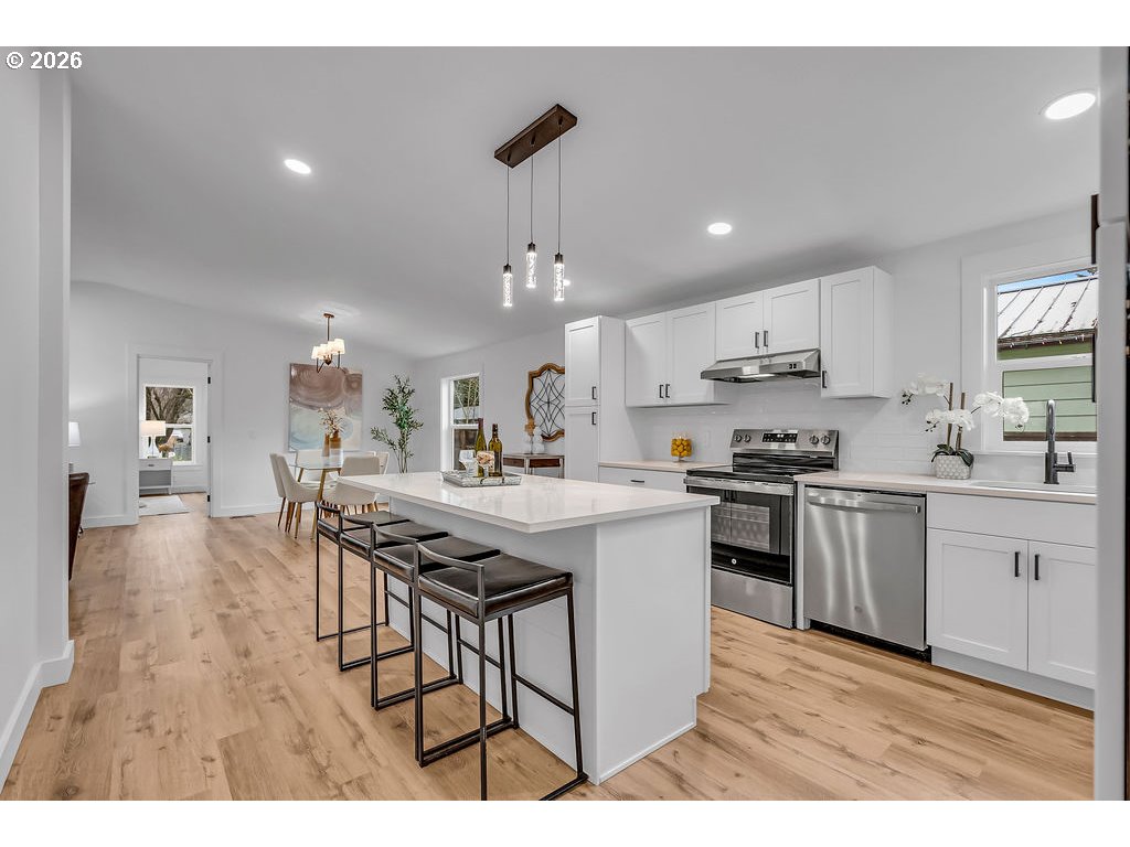 241 Northwest Wade Street Estacada, OR 97023 - Photo 19 of 45 a kitchen with stainless steel appliances kitchen island a stove a sink dishwasher a refrigerator and white cabinets with wooden floor