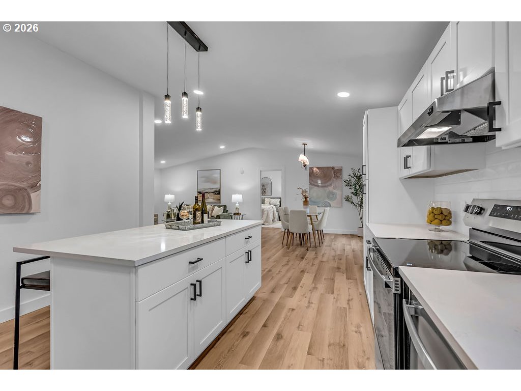 241 Northwest Wade Street Estacada, OR 97023 - Photo 21 of 45 a kitchen with kitchen island a stove a sink dishwasher and a dining table with wooden floor