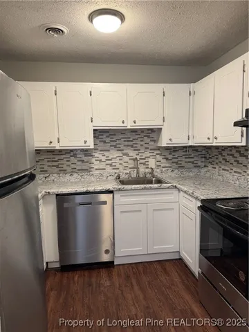 a kitchen with granite countertop a sink stainless steel appliances and cabinets