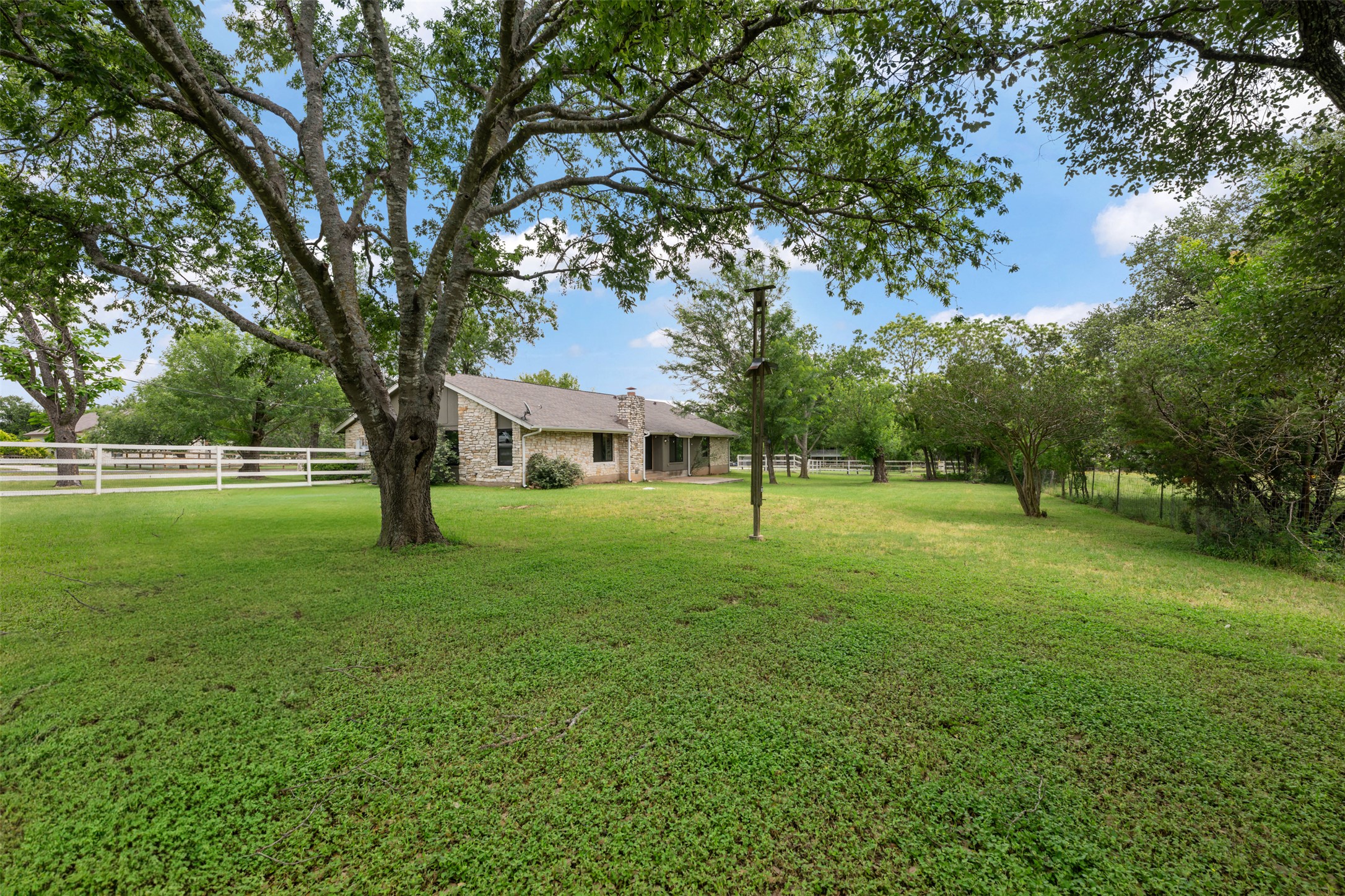 1600 Pin Oak Lane Round Rock, TX 78681 - Photo 35 of 40 Expansive green lawn with mature trees and a white multi-rail fence