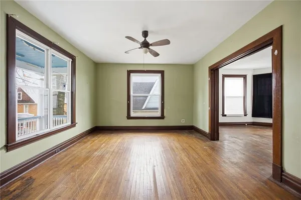 an empty room with wooden floor chandelier and windows