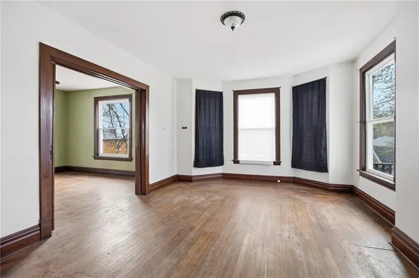 a view of an empty room with glass door and wooden floor