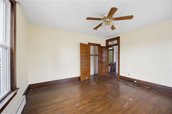 a view of empty room with wooden floor and ceiling fan