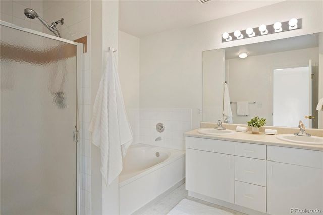 a en suite bathroom with a double vanity sink a mirror and a bathtub