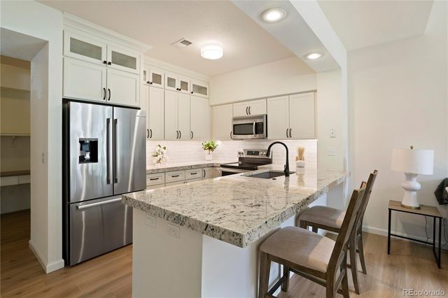 a kitchen with granite countertop a refrigerator a stove a sink a dining table and chairs