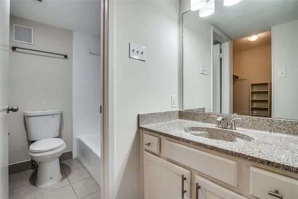 a bathroom with a granite countertop toilet sink and mirror