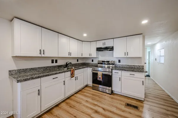 a kitchen with granite countertop white cabinets and white appliances