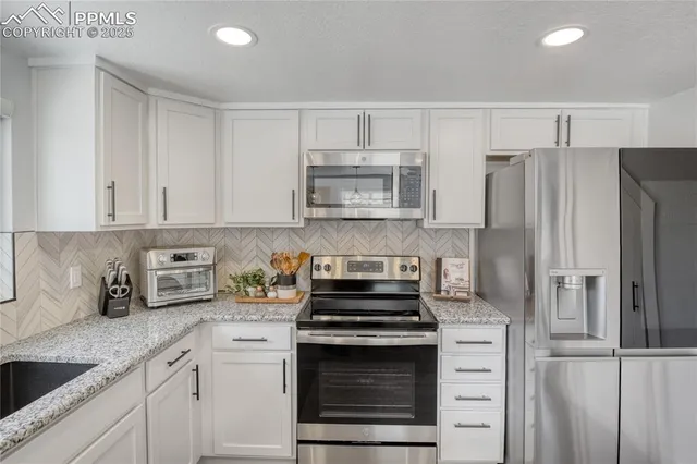 a kitchen with refrigerator a microwave a sink and cabinets