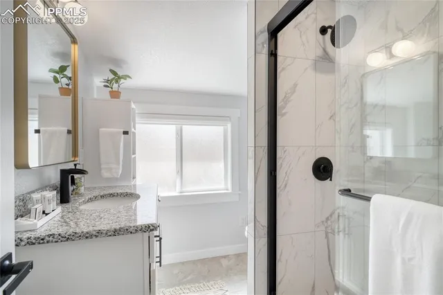 a bathroom with a granite countertop sink a mirror and shower