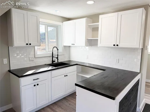 a kitchen with granite countertop a sink and white cabinets