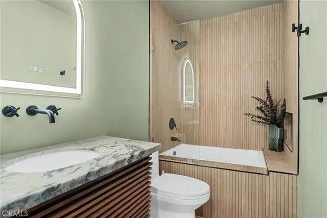 a bathroom with a granite countertop sink a toilet and shower