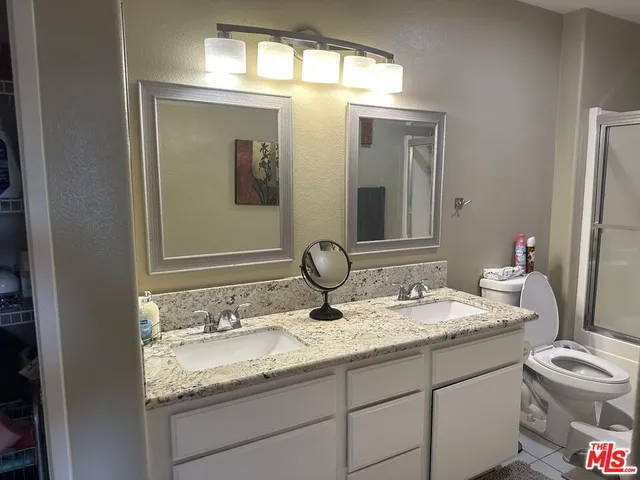 a bathroom with a granite countertop toilet sink and mirror