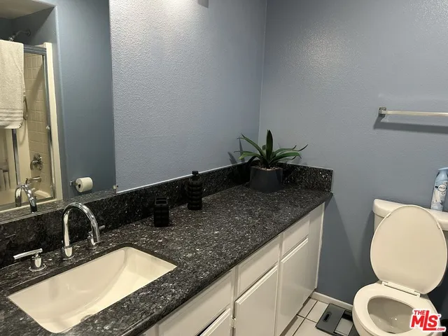 a bathroom with a granite countertop toilet sink and mirror