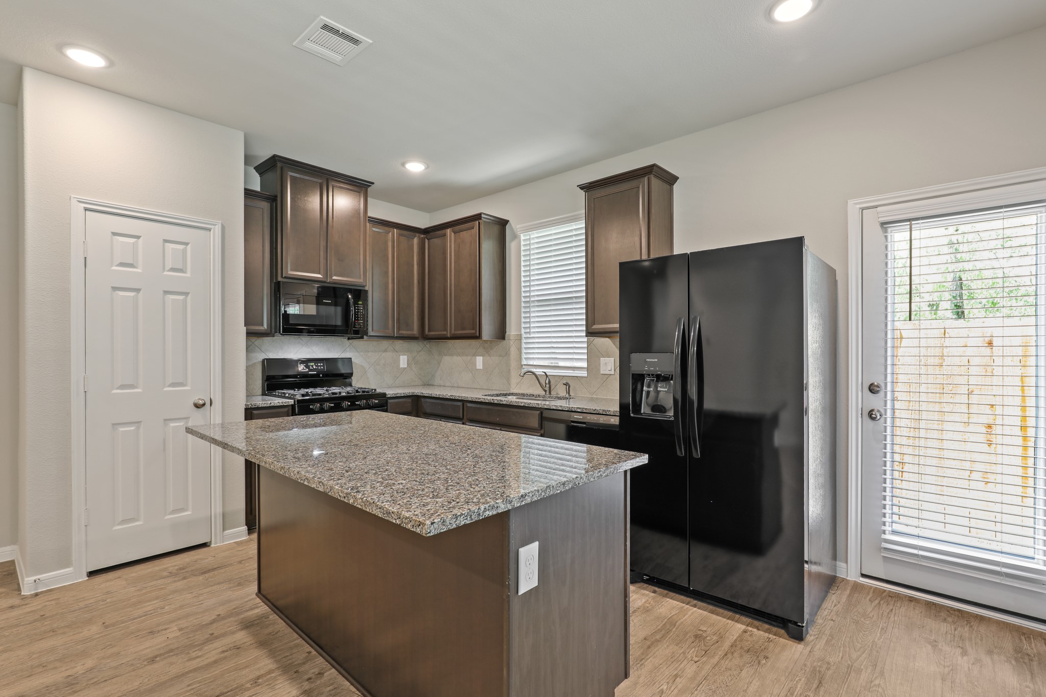 13514 Axel Lane Houston, TX 77047 - Photo 11 of 34 a kitchen with granite countertop a refrigerator a sink a stove a microwave and wooden floor