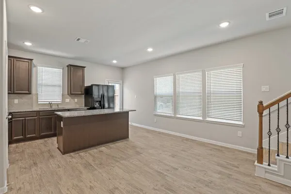 a large kitchen with kitchen island granite countertop a stove top oven a sink a counter space and cabinets