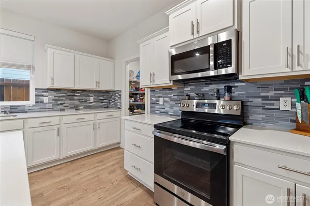 a kitchen with stainless steel appliances granite countertop grey cabinets a stove a sink and dishwasher