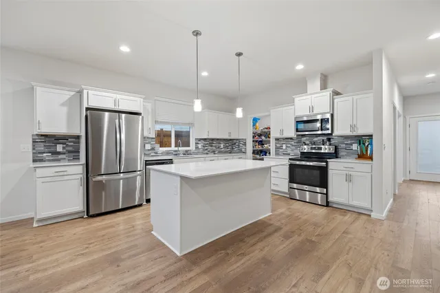 a kitchen with refrigerator a microwave and white cabinets