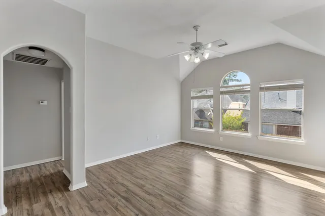 a view of an empty room with a window and wooden floor