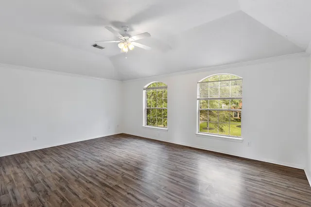 a view of an empty room with wooden floor and window