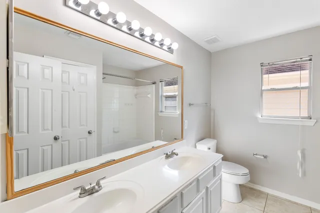 a bathroom with a toilet a sink a mirror and a shower