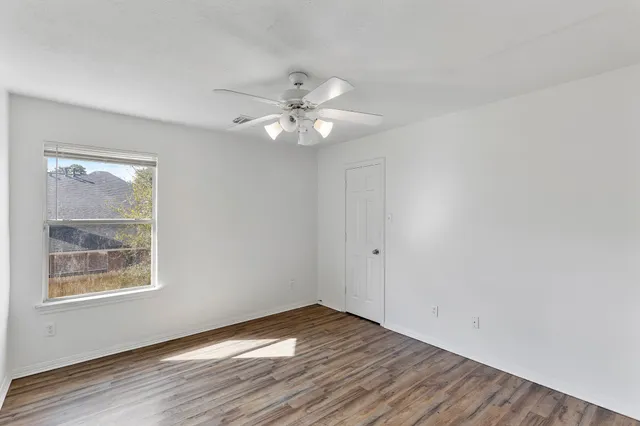 a view of an empty room with wooden floor and a window