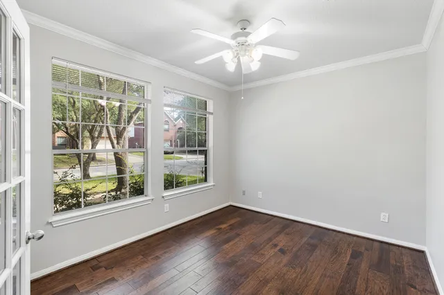an empty room with wooden floor and windows