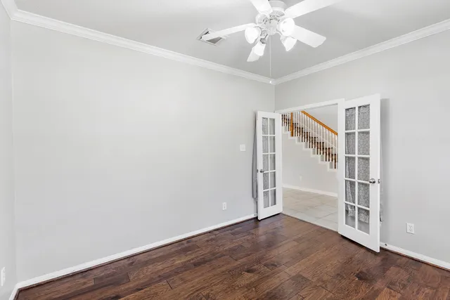 an empty room with wooden floor chandelier fan and windows