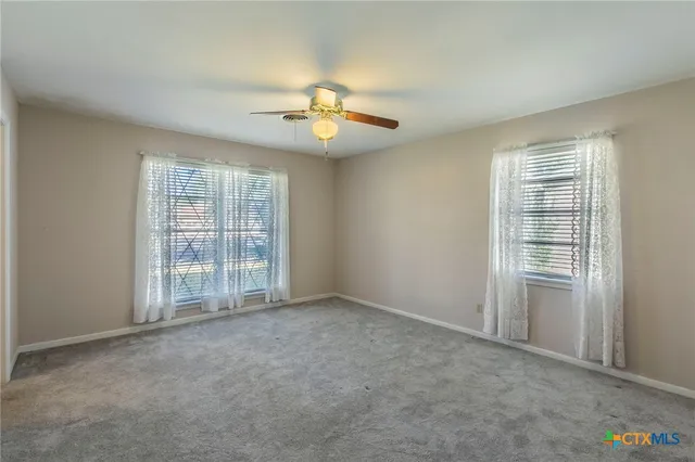 an empty room with windows and fan