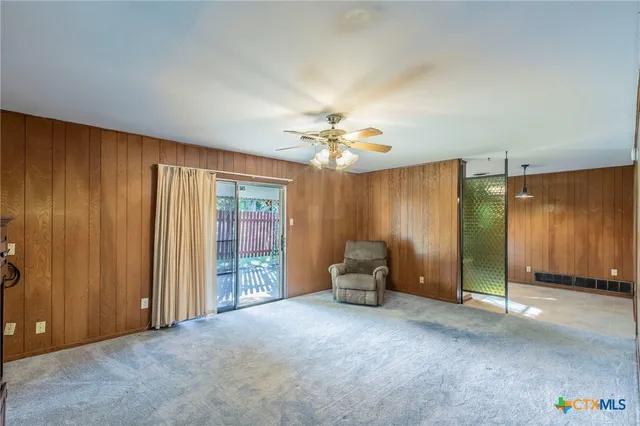 an empty room with windows and chandelier fan
