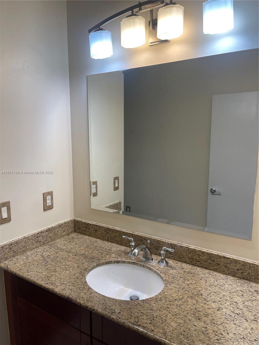 7280 Southwest 90th Street, Unit 708 Miami, FL 33156 - Photo 12 of 18 a bathroom with a granite countertop sink and a mirror