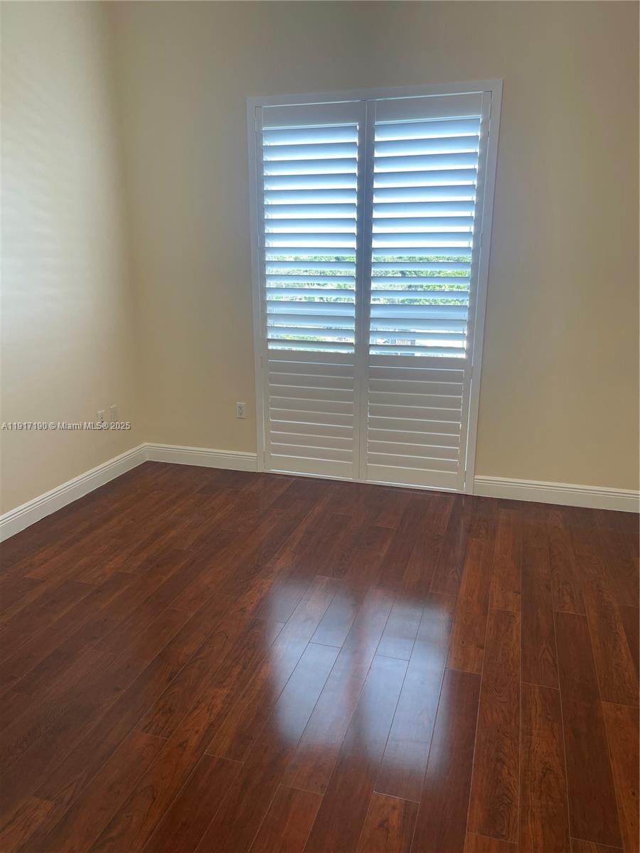 7280 Southwest 90th Street, Unit 708 Miami, FL 33156 - Photo 7 of 18 an empty room with wooden floor and windows