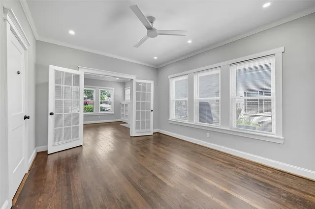 a view of an empty room with wooden floor and a window