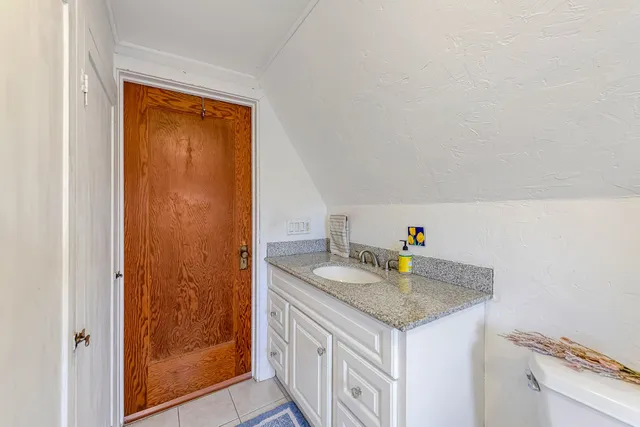 a bathroom with a granite countertop sink mirror vanity and toilet