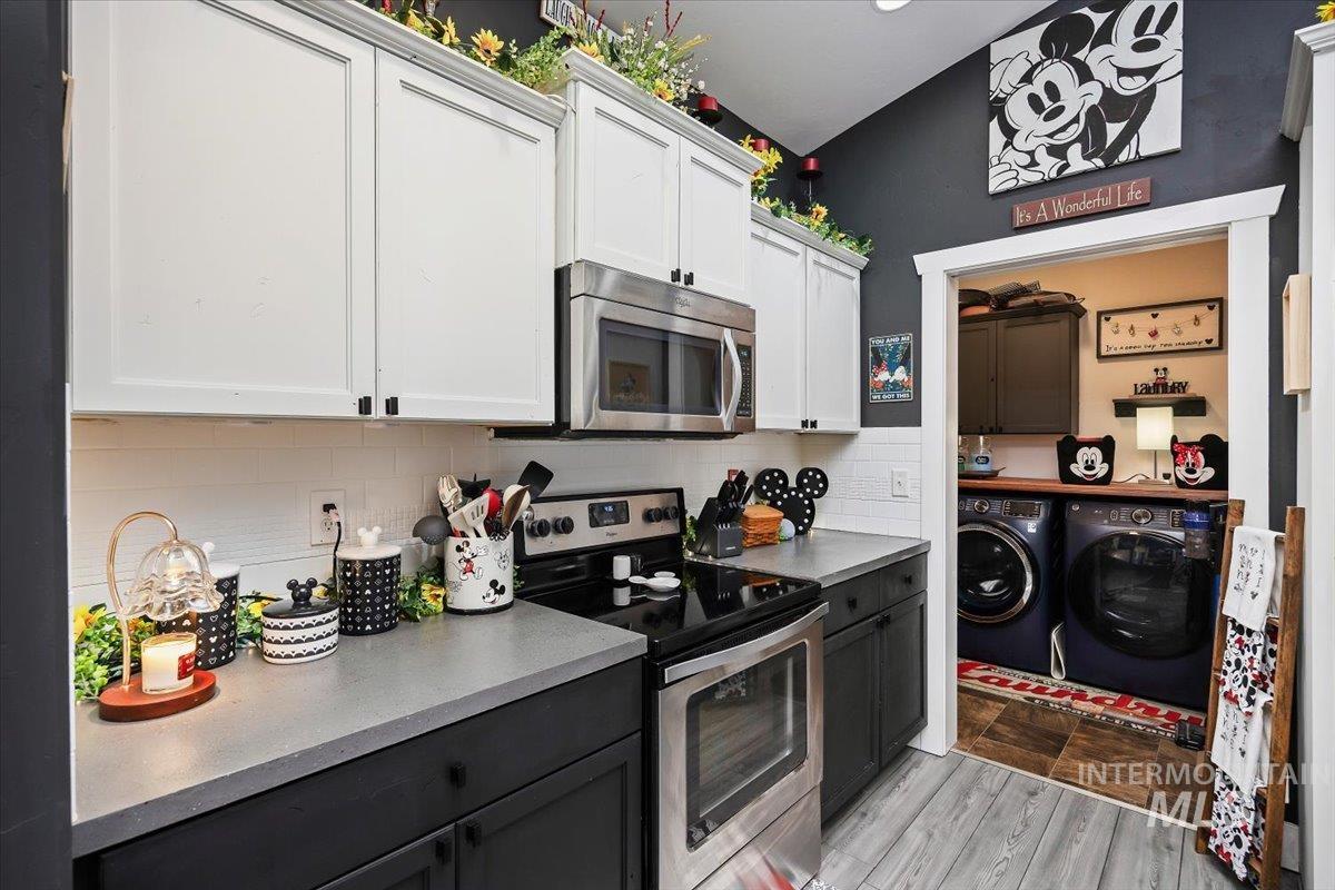 389 Arrow Street Twin Falls, ID 83301 - Photo 12 of 34 Two tone kitchen with stainless steel appliances, two tone cabinets, separate washer and dryer, light wood-style flooring, and tasteful backsplash