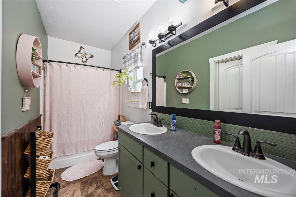 389 Arrow Street Twin Falls, ID 83301 - Photo 17 of 34 Full bath featuring double vanity, shower / bath combo with shower curtain, and a wainscoted wall