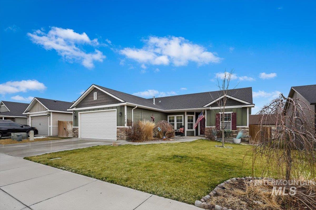 389 Arrow Street Twin Falls, ID 83301 - Photo 2 of 34 View of front of home with stone siding, a front lawn, driveway, and an attached garage