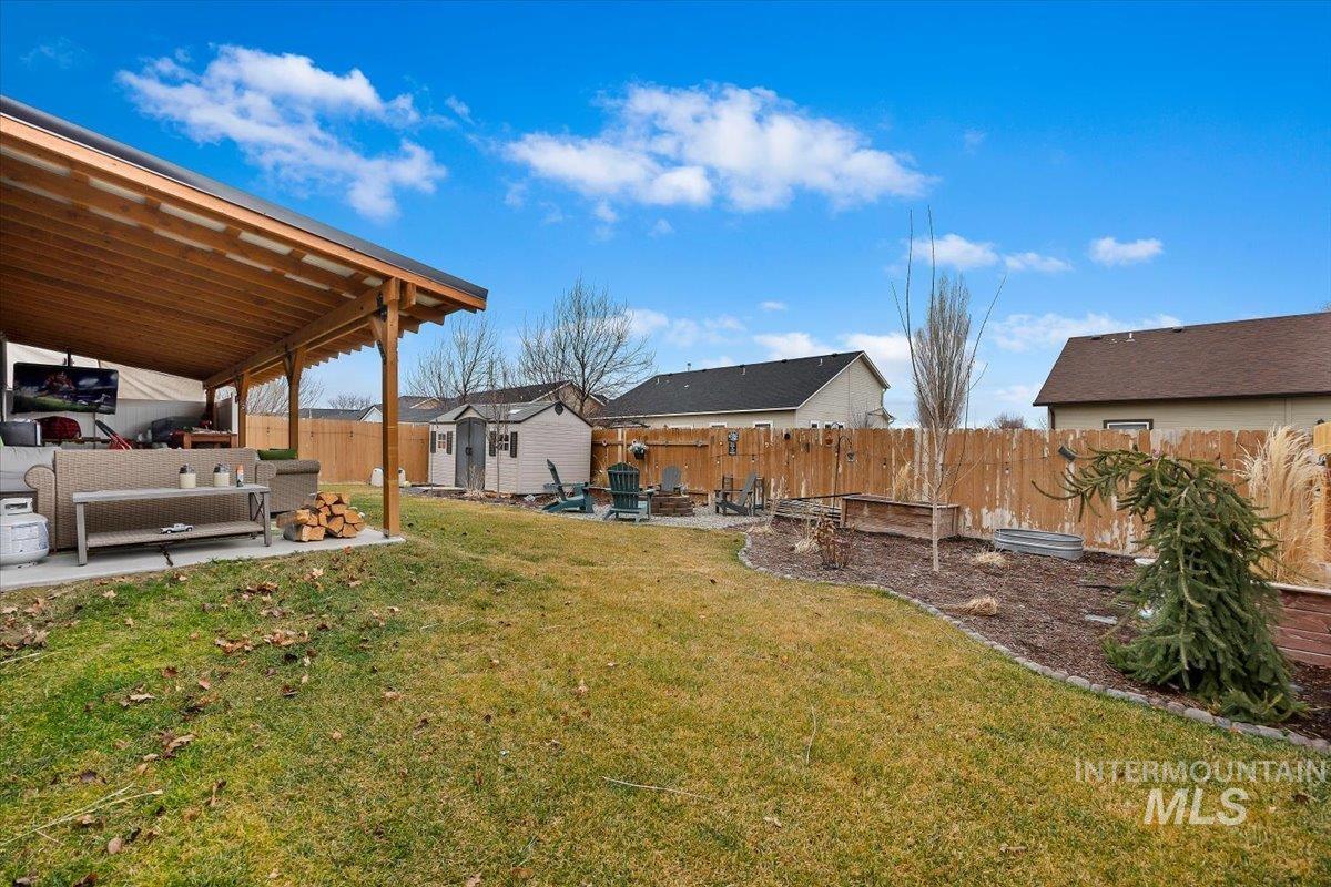 389 Arrow Street Twin Falls, ID 83301 - Photo 23 of 34 Fenced backyard with a patio area, an outdoor living space with a fire pit, and a storage unit
