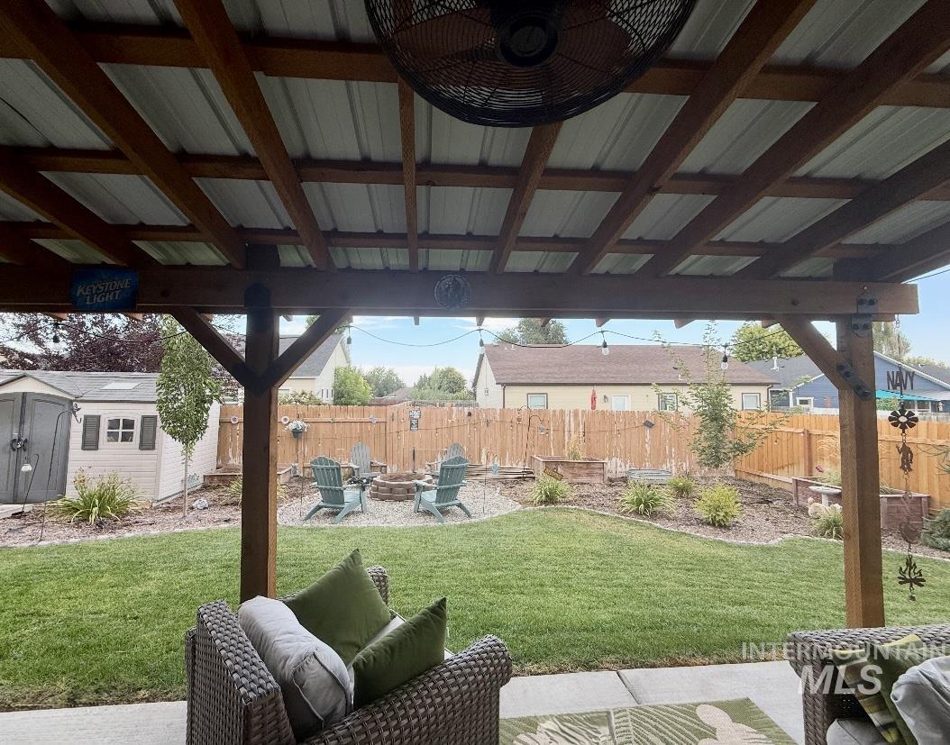 389 Arrow Street Twin Falls, ID 83301 - Photo 31 of 34 Fenced backyard featuring a patio area, a storage unit, and an outdoor living space with a fire pit
