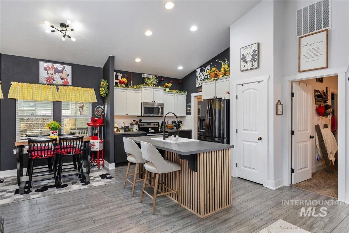 389 Arrow Street Twin Falls, ID 83301 - Photo 10 of 34 Kitchen featuring a kitchen breakfast bar, white cabinetry, an island with sink, dark countertops, and stainless steel appliances