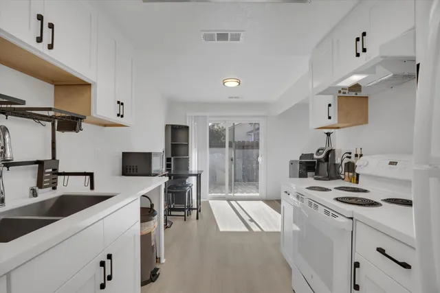 a kitchen with a sink a stove and white cabinets