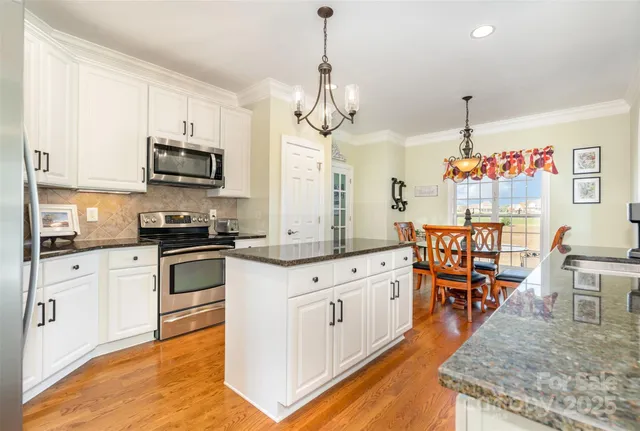 a kitchen with stainless steel appliances granite countertop a stove top oven a sink a dining table and chairs with wooden floor