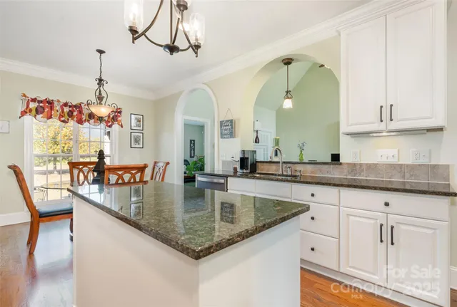a view of a kitchen with granite countertop a center island a stove and a wooden floors