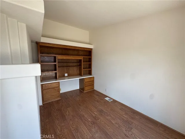 a view of an empty room with wooden floor and a fireplace