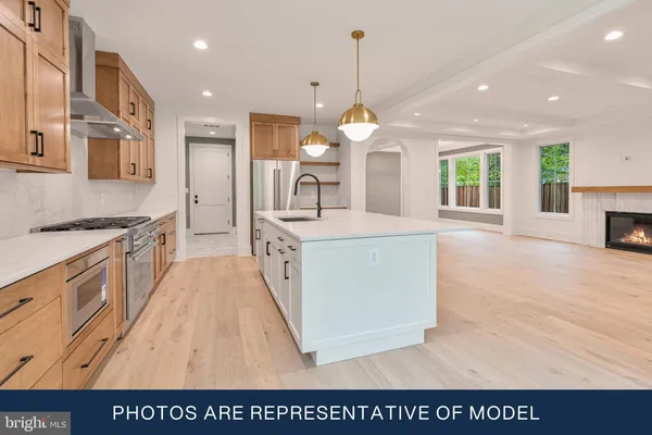 a large white kitchen with stainless steel appliances granite countertop a stove and a wooden floors