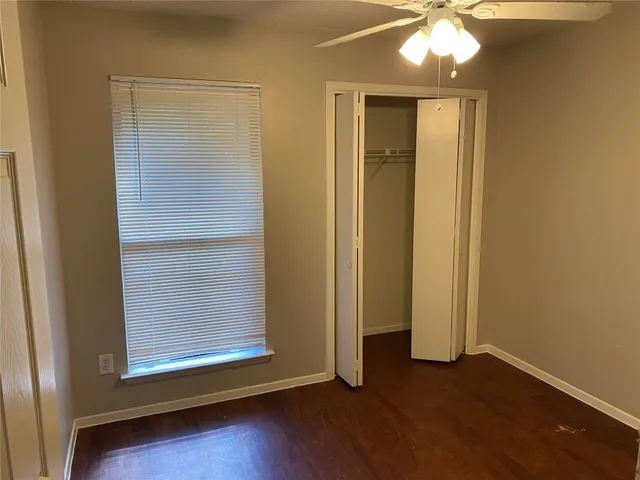 an empty room with wooden floor and closet area
